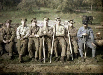 Canadian soldiers with a cant hook are sitting on the trunk of a tree for a sawmill, Quesmy, Oise, France, 1917